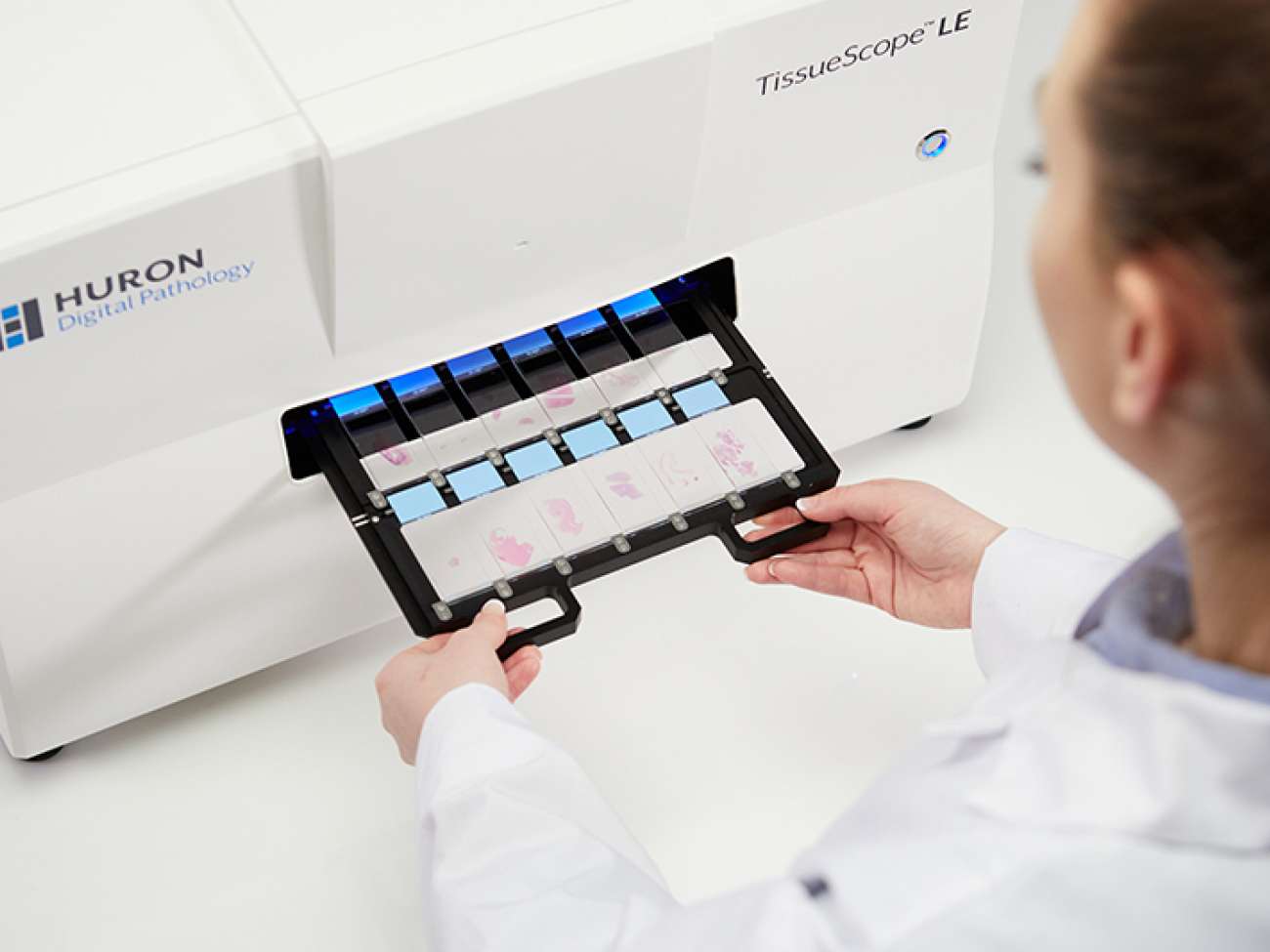 A histotechnologist inserts a number of digital biopsy slides into a scanner. Photo courtesy of Huron Digital Pathology