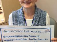 Maura's sign reads: Help someone feel better by encouraging any form of regular exercise; invite them to go for a walk, meet at the gym or attend a yoga classthumbnail image.