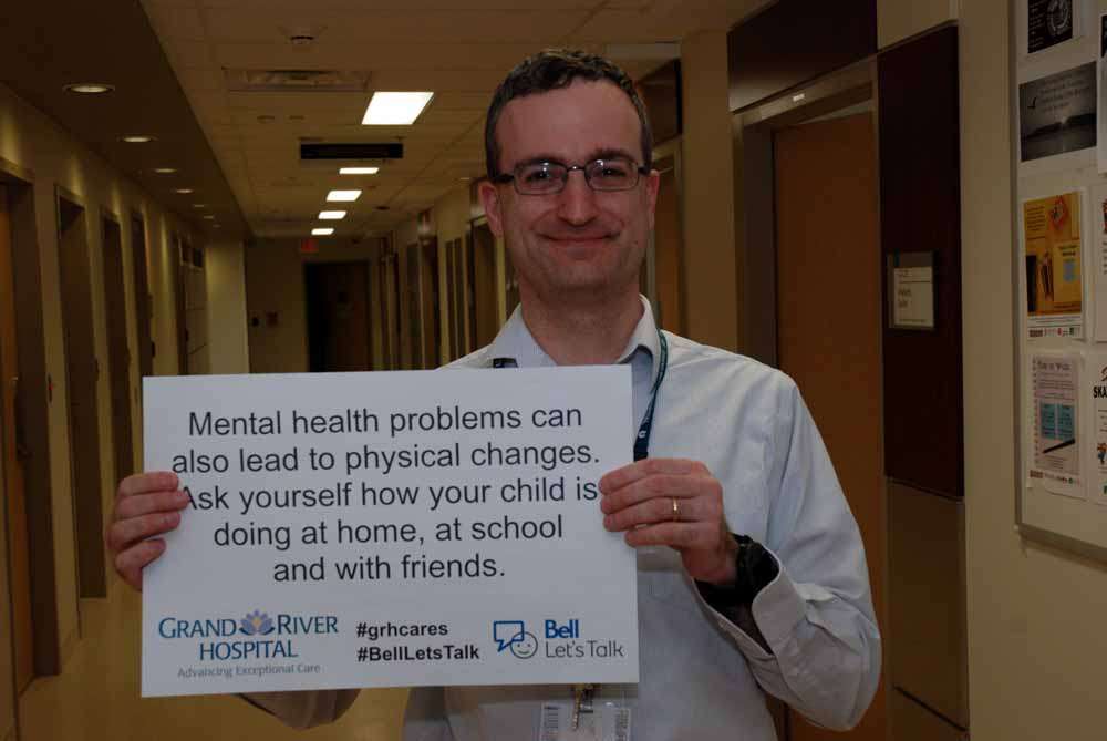 A care provider with a sign reading: Mental health problems can also lead to physical changes. Ask yourself how your child is doing at home, at school and with friends.