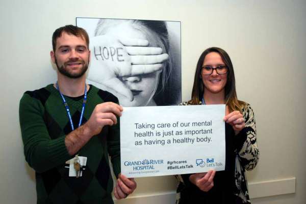 Two care providers holding a sign reading: Taking care of our mental health is just as important as having a healthy body.