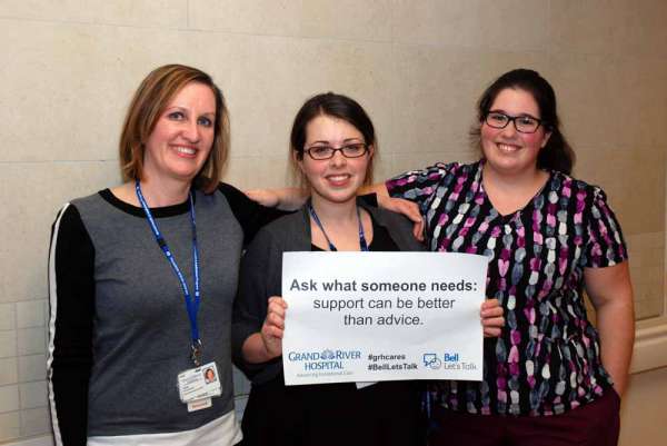 Three care providers holding a sign reading: ask what someone needs- support can be better than advice.