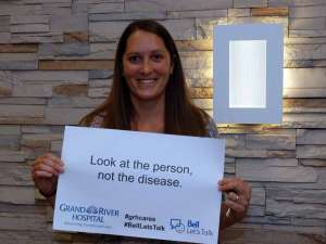 A staff member holding a sign reading: look at the person, not the disease