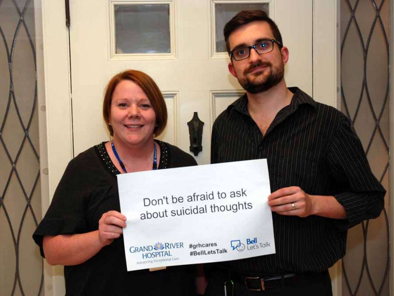 Two care providers holding a sign reading: don't be afraid to ask about suicidal thoughts.