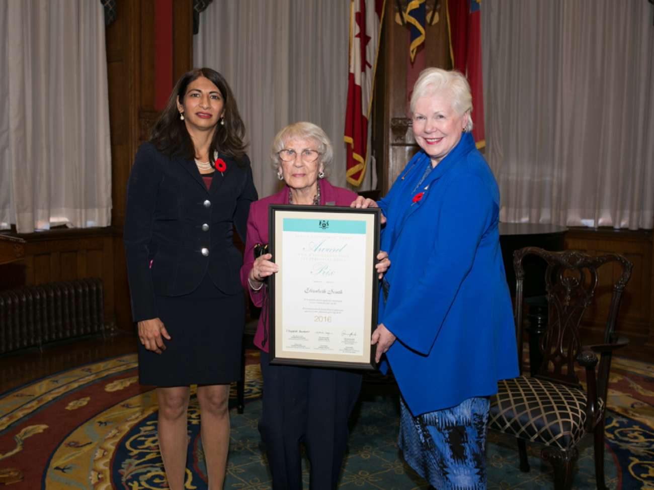 Betty South receives her award from the Hon. Dipika Damerla, Minister Responsible for Seniors Affairs (left) and the Hon. Elizabeth Dowdeswell, Lieutenant Governor of Ontario (right). Photo courtesy of the Government of Ontario.