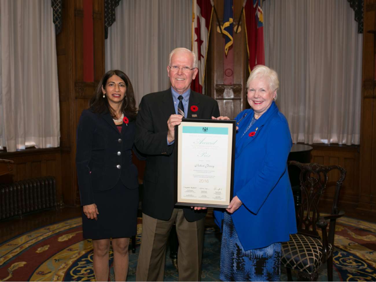 Robert Povey receives his award from the Hon. Dipika Damerla, Minister Responsible for Seniors Affairs (left) and the Hon. Elizabeth Dowdeswell, Lieutenant Governor of Ontario (right). Photo courtesy of the Government of Ontario.