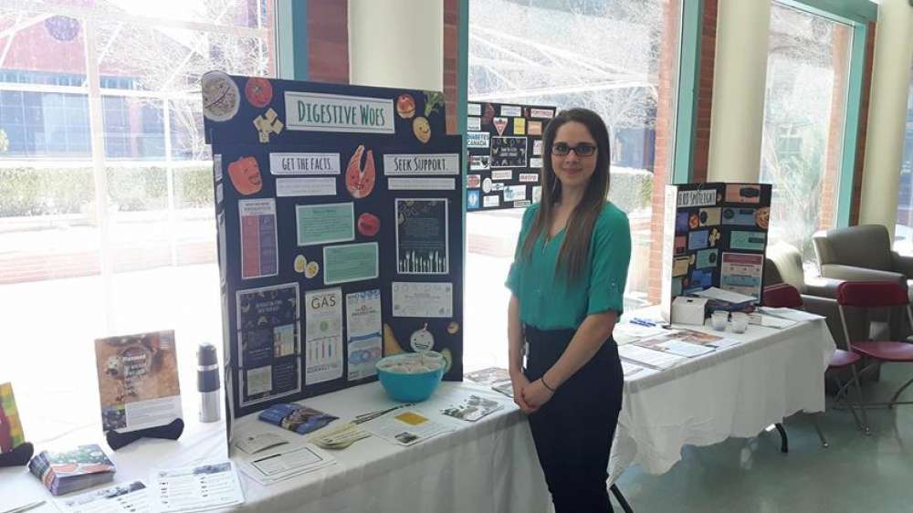 A dietetic intern standing at a table display