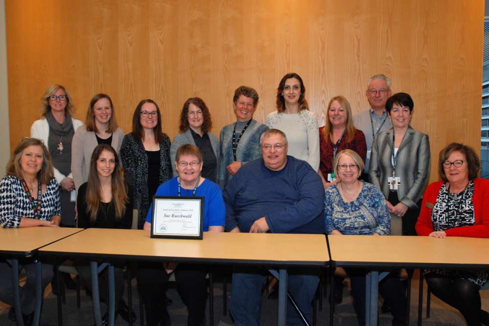 Sue Rueckwald's colleagues join her as she receives her award of excellence.