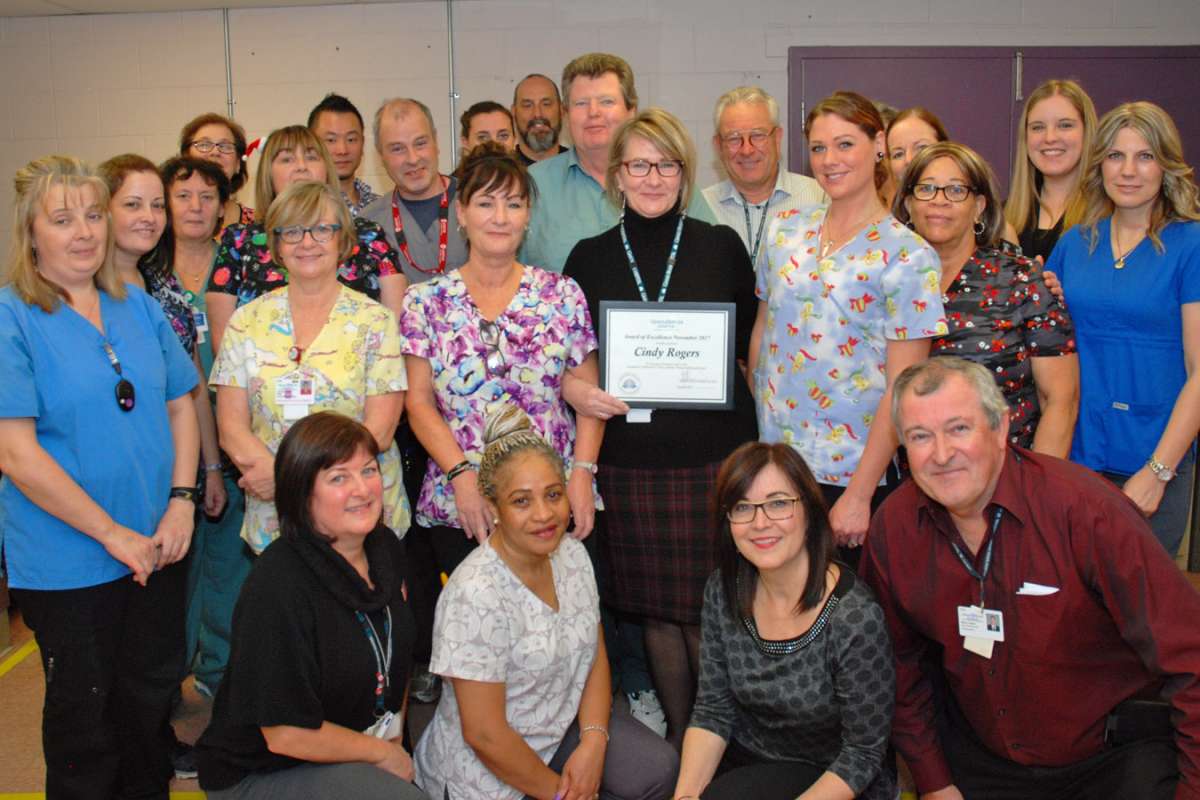 Staff from environmental services and other leaders from the hospital congratulate Cindy Rogers on her award of excellence win.