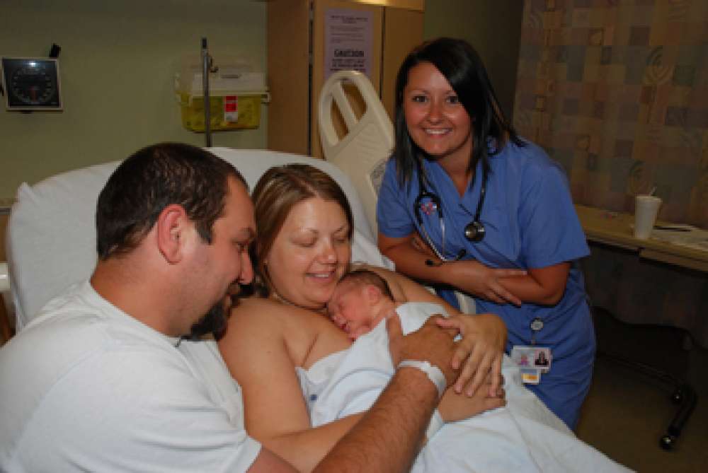 A photo of a nurse with a family and their new baby
