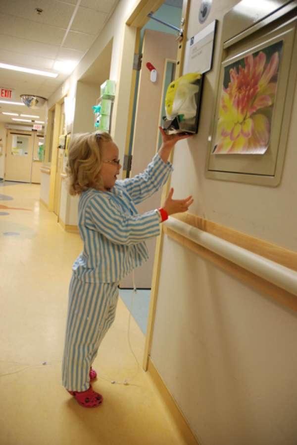 A photo of a child using a hand sanitizer dispenser