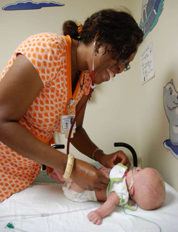 A photo of a care provider giving a baby a check-up.