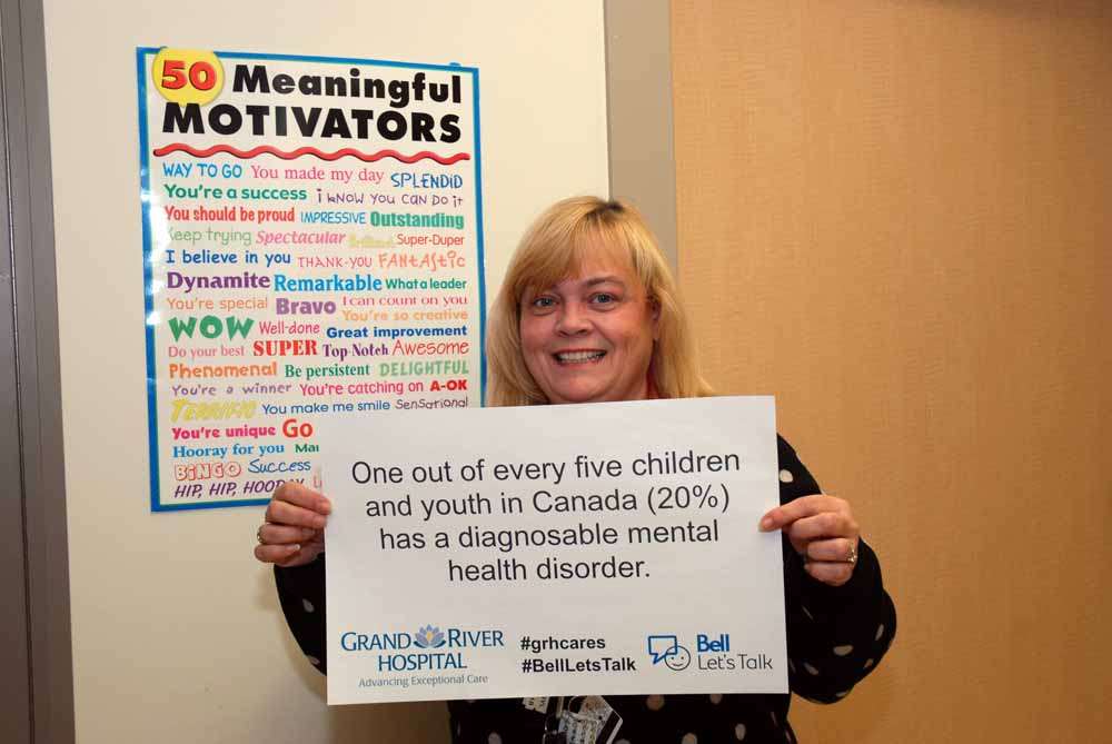 A care provider with a sign reading: One out of every five children and youth in Canada (20%) has a diagnosable mental health disorder.