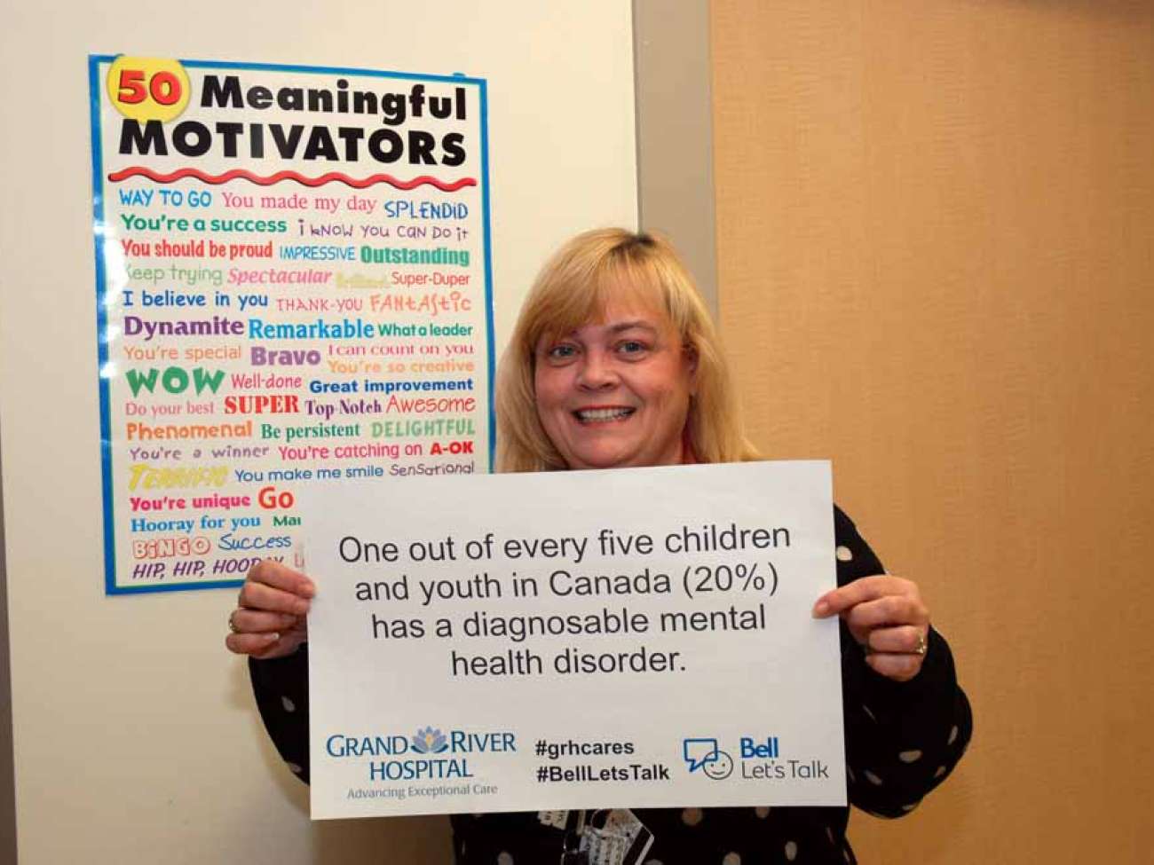 A care provider with a sign reading: One out of every five children and youth in Canada (20%) has a diagnosable mental health disorder.