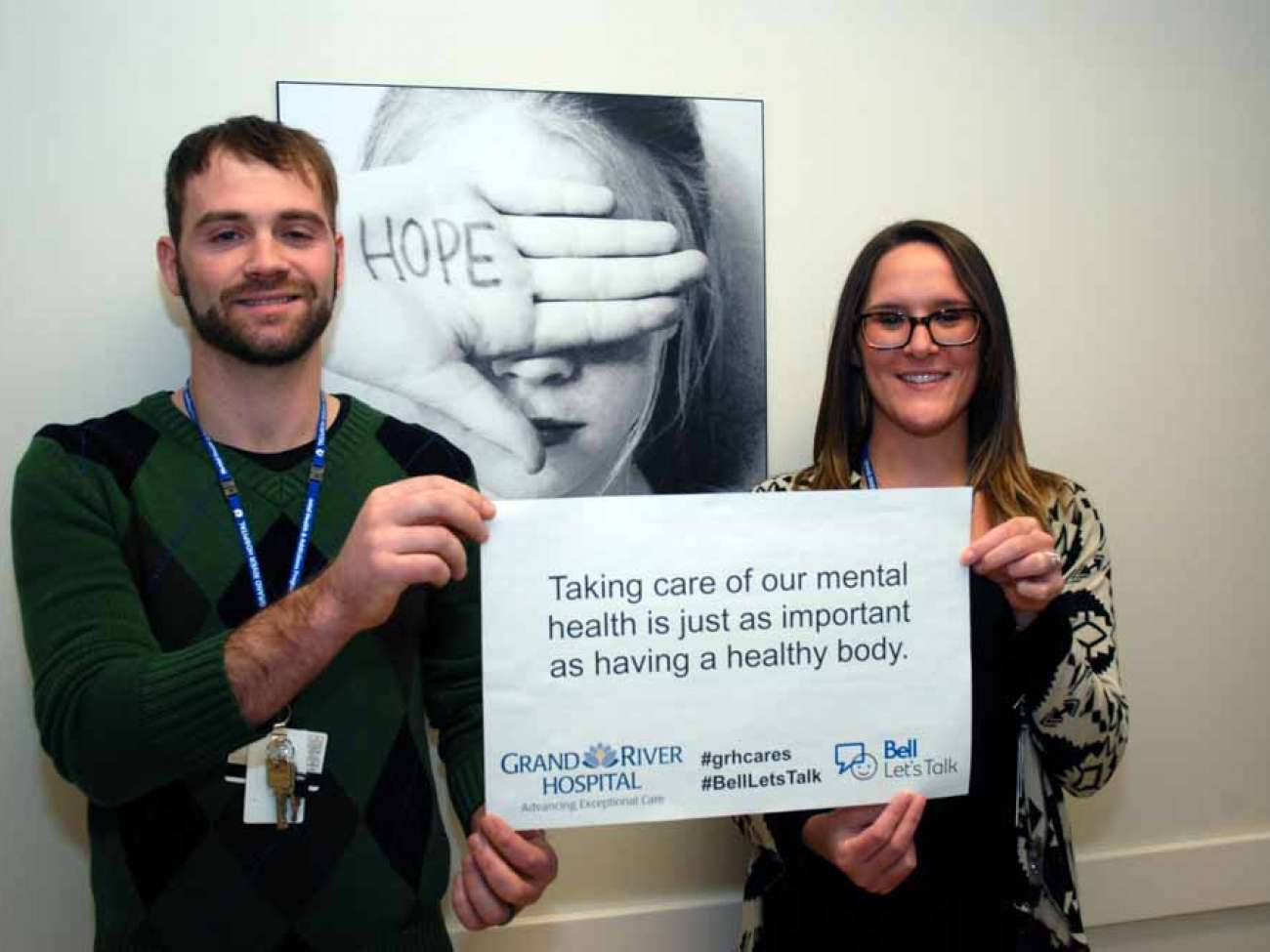 Two care providers holding a sign reading: Taking care of our mental health is just as important as having a healthy body.