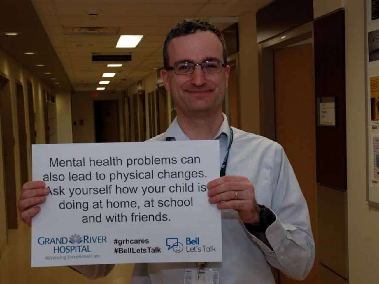 A care provider with a sign reading: Mental health problems can also lead to physical changes. Ask yourself how your child is doing at home, at school and with friends.