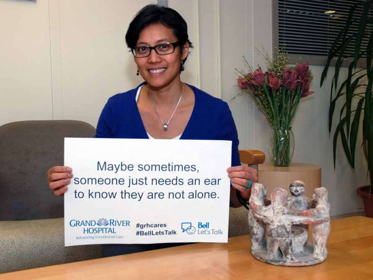 A care provider holding a sign reading: Maybe sometimes someone just needs an ear to know they are not alone.