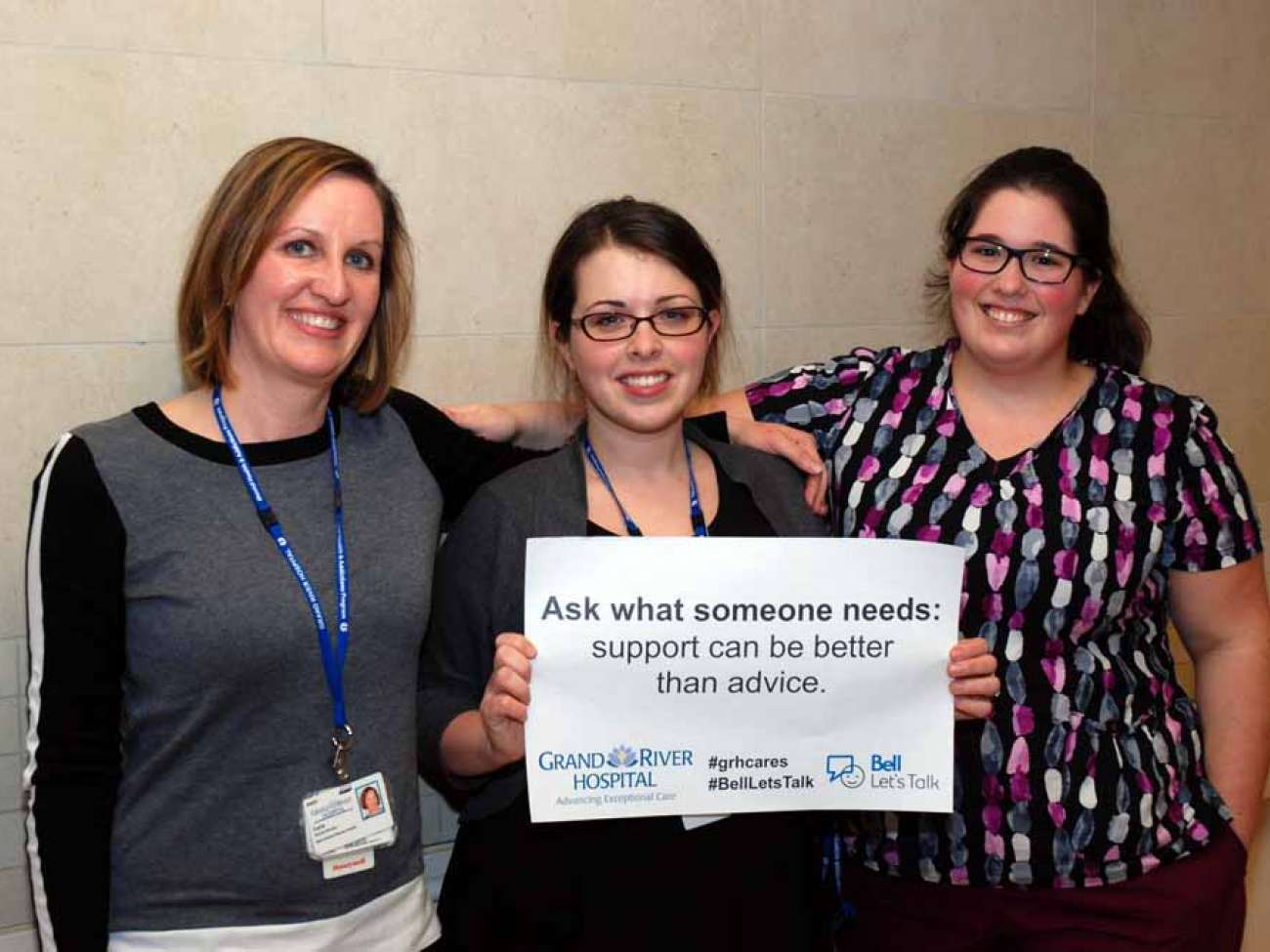 Three care providers holding a sign reading: ask what someone needs- support can be better than advice.