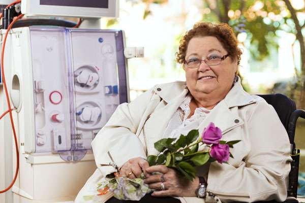 A photo of a renal patient sitting beside a dialysis machine