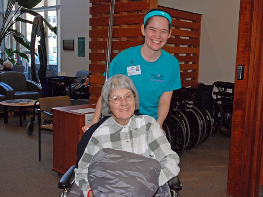 A photo of a volunteer pushing a patient in a wheel chair