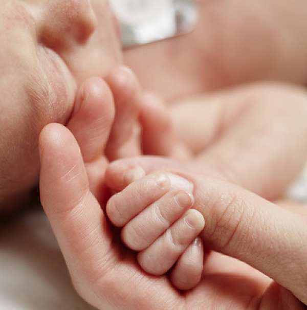 A nurse holding a baby's hand