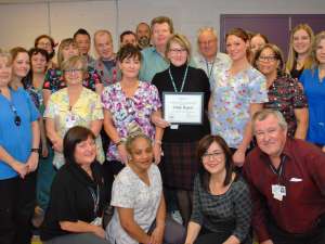 Staff from environmental services and other leaders from the hospital congratulate Cindy Rogers on her award of excellence win.